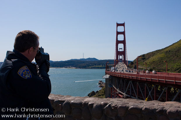 Policeman uses a radar gun to catch speeders crossing the Golden Gate Bridge
