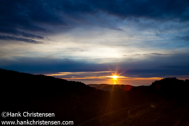 The sun sets over the Pacific Ocean beyond green hills, Purisima Creek Redwoods Open Space Preserve