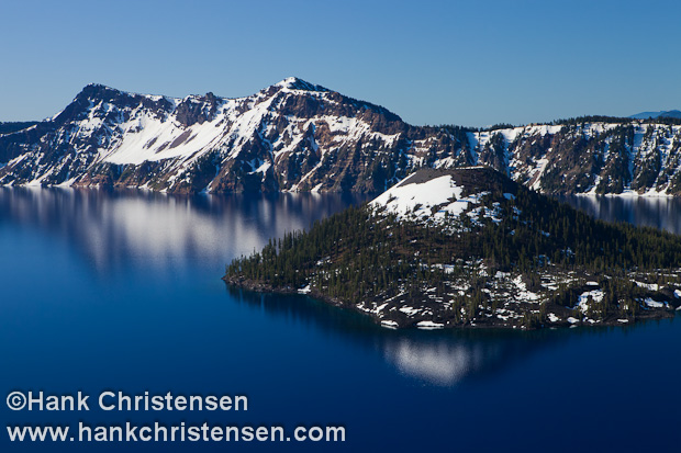 Snow-capped Wizard Island sits in the deep blue waters of Crater Lake