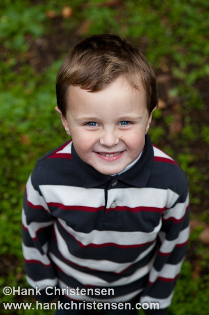 A portrait of a boy smiling from above.  Green moss background.