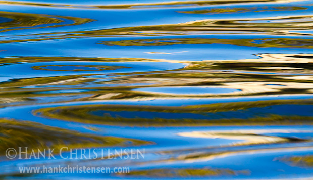 Fall colors are reflected in the surface of moving water ripples. The ripples turn simple reflections into endless patterns.