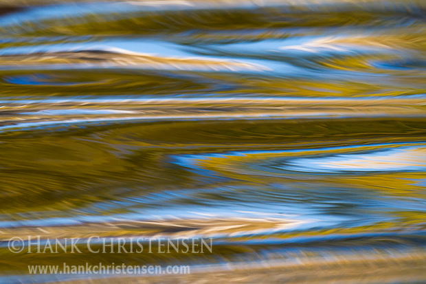 Fall colors are reflected in the surface of moving water ripples. The ripples turn simple reflections into endless patterns.