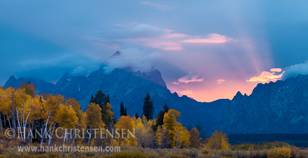 Dramatic light bursts from behind the Tetons at sunset. Thick smoke and haze from nearby forest fires create God beams as the sun drops behind the horizon, Grand Teton National Park