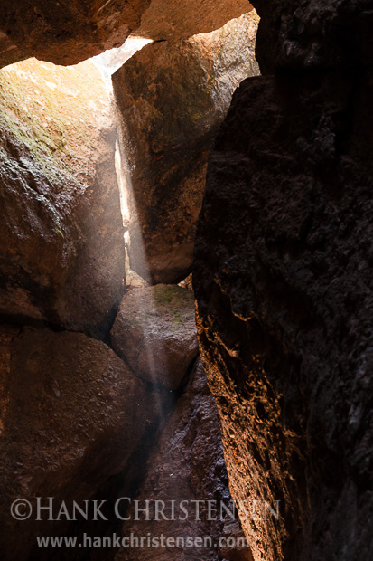 Light steams down through the ceiling at the entrance to Bear Gulch Cave, Pinnacles National Park