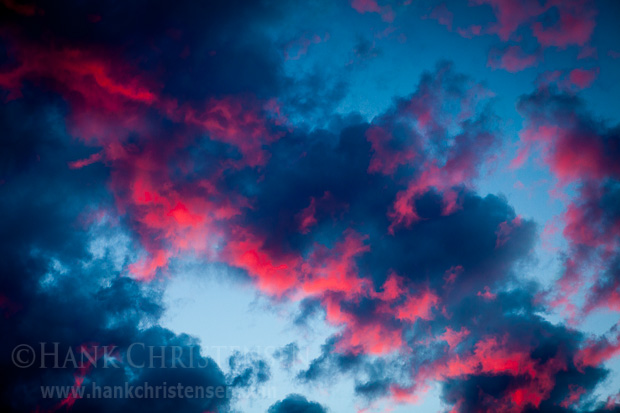 Storm clouds are bottom lit from the setting sun