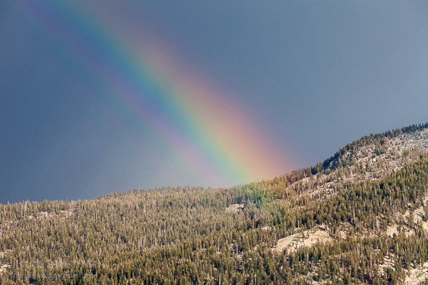 A rainbow peaks through the dark clouds of an afternoon thunder storm, Yosemite National Park