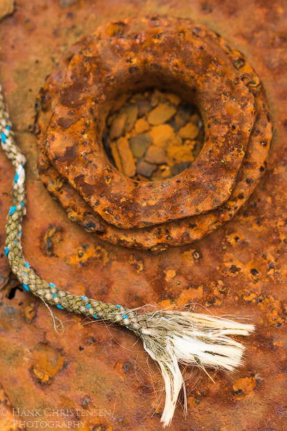 A frayed rope lies against dark rusted metal in a boat repair yard