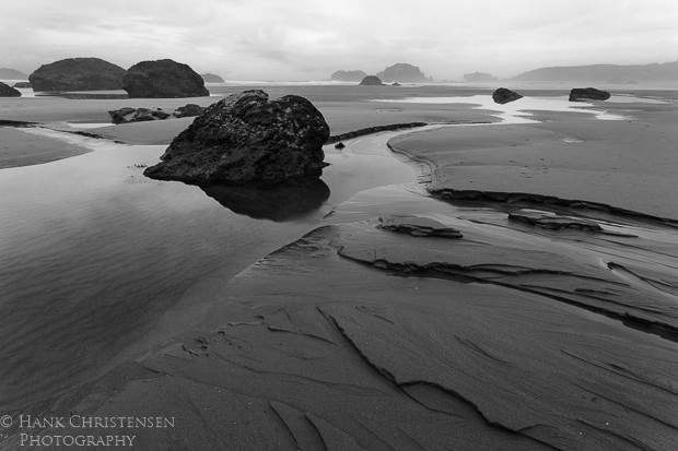 A low tide exposes large stones and carved sand along Bandon Beach, Oregon