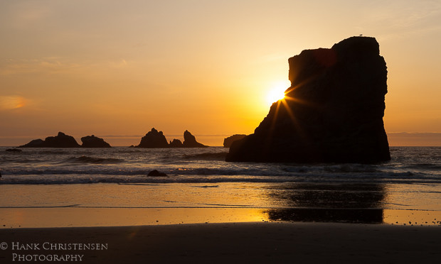 The setting sun at Bandon Oregon turns the sky an orange pink and turns the sea stacks into silhouettes.