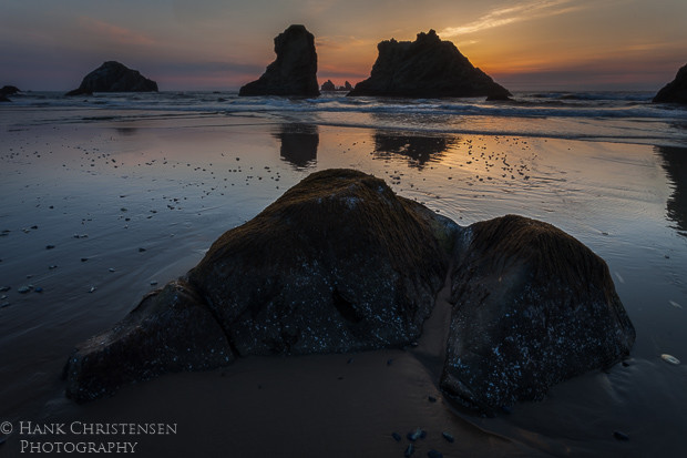 The setting sun at Bandon Oregon turns the sky an orange pink and turns the sea stacks into silhouettes.
