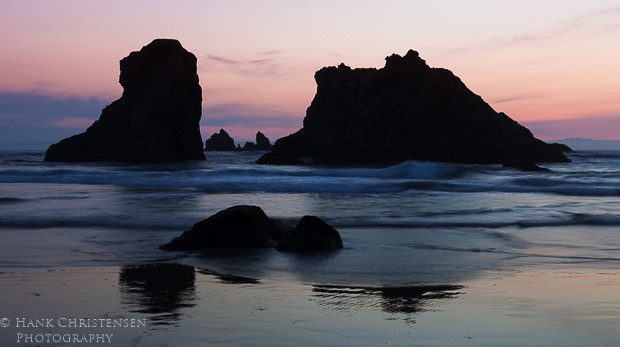 The setting sun at Bandon Oregon turns the sky an orange pink and turns the sea stacks into silhouettes.