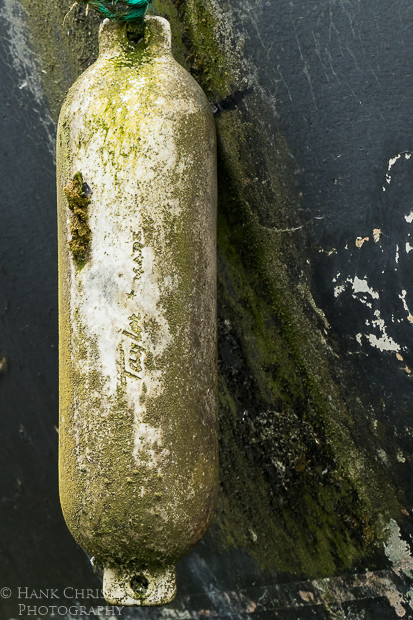 An old weathered bumper hangs off the side of a paint-peeling boat